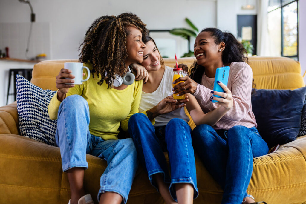 Three cheerful multiracial female friends enjoying free time together at home. Female friendship concept
